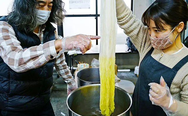 生地の端から順に染料に浸す時間を変え、グラデーションになるように染めていきます。天然の染料を繊維に定着させる「媒染」という工程を挟み、再度染色します。徐々に色づいていく様子にワクワクします。