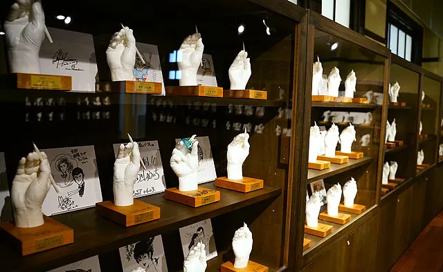 京都国際マンガミュージアム：2階「ギャラリー6」では、ちばてつや先生を筆頭に、イベント等でマンガミュージアムに来館したマンガ家さんの石膏手型がずらりと陳列。直筆イラストとあわせてチェックしてみてください