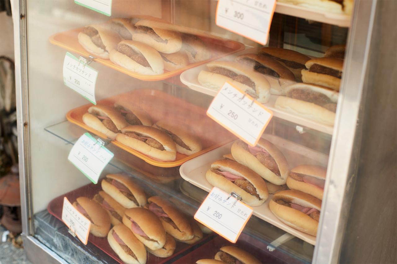 ガラスケースにはメンチカツサンドなど数種類の総菜パンが並ぶ。